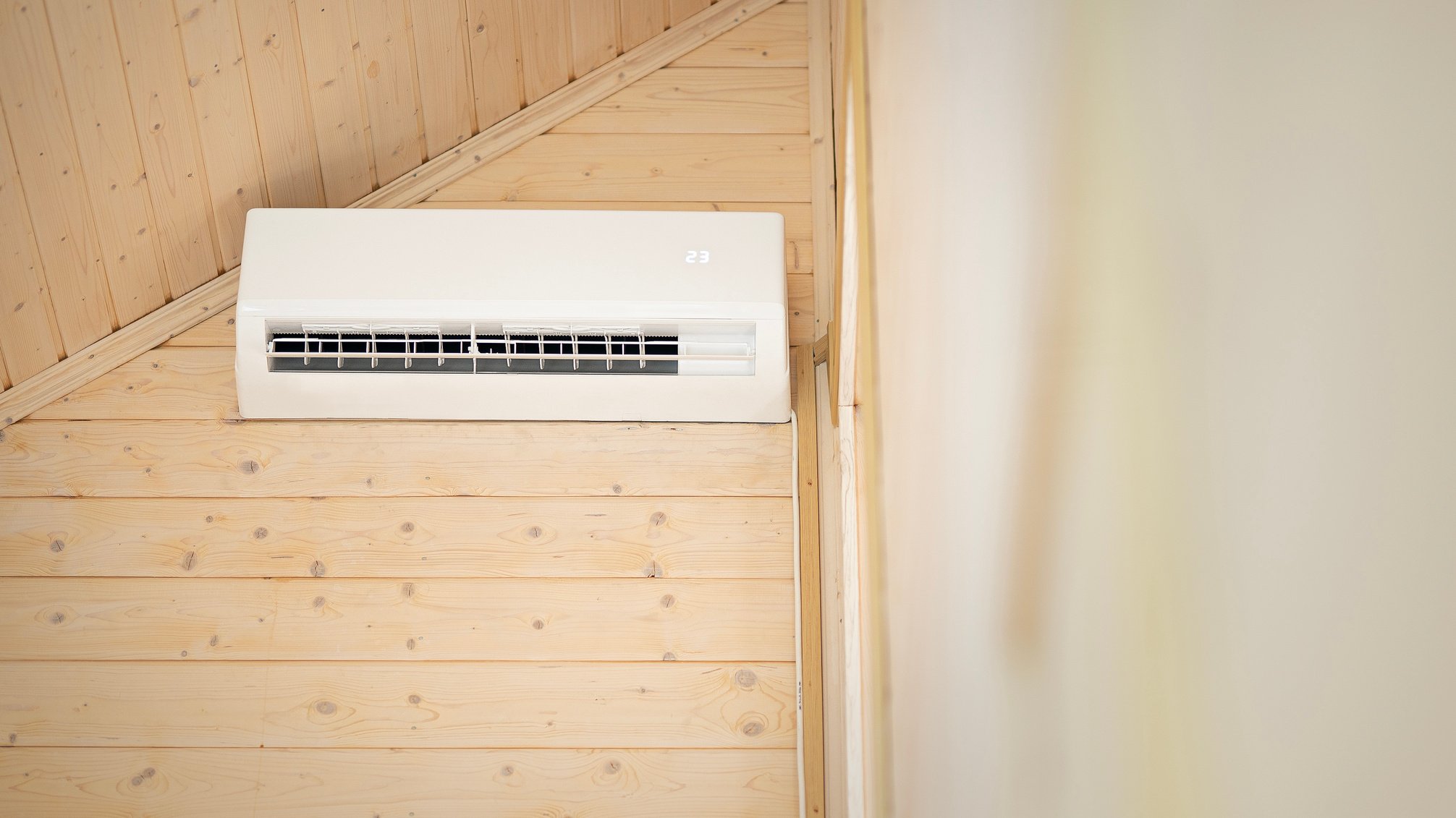 White air conditioner on the wall of a wooden house. Split air conditioner